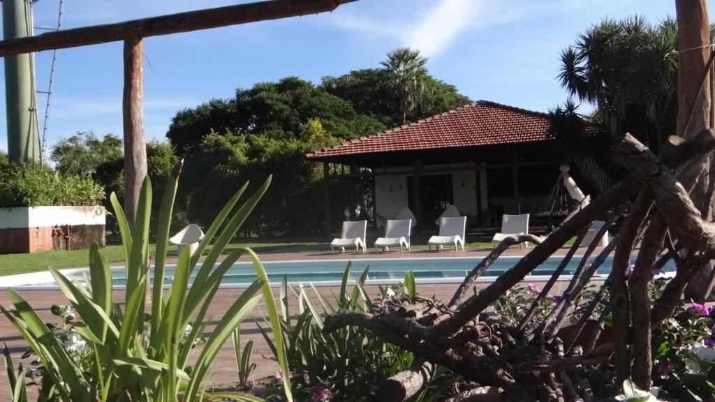 a pool with white chairs and a house at Pousada Fazenda Xaraés in Todos os Santos