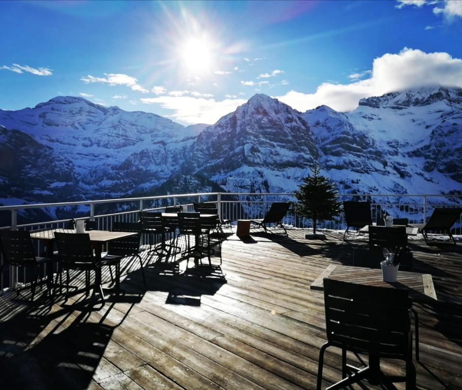una terraza con mesas y sillas y montañas cubiertas de nieve en Hôtel Plein Ciel, en Champéry