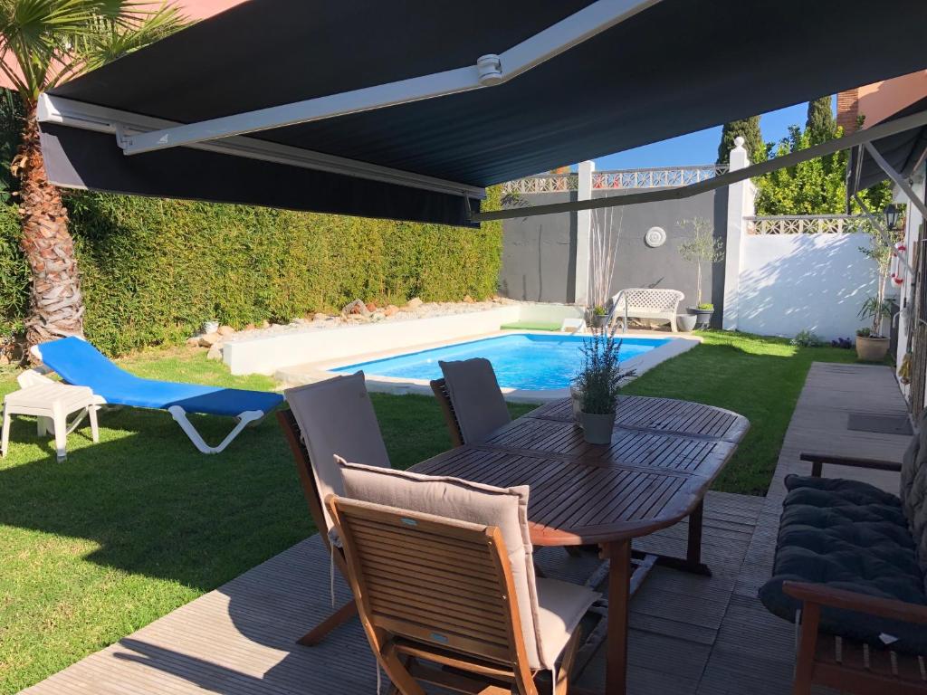 un patio con mesa y sillas y una piscina en Chalet Palacio Valdes, en Torremolinos