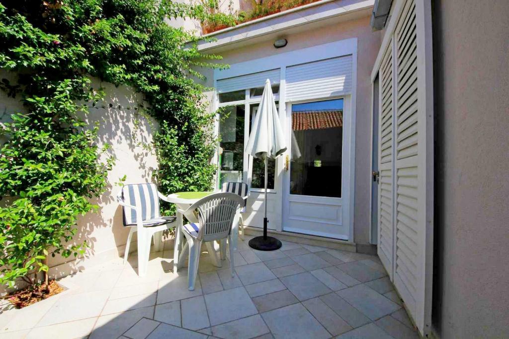 Un patio con una mesa y sillas y una sombrilla. en Studios Mimoza, en Dubrovnik