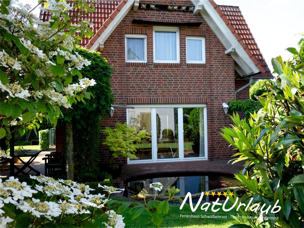 a brick house with white flowers in front of it at Ferienhaus Schwalbenrast in Lembruch