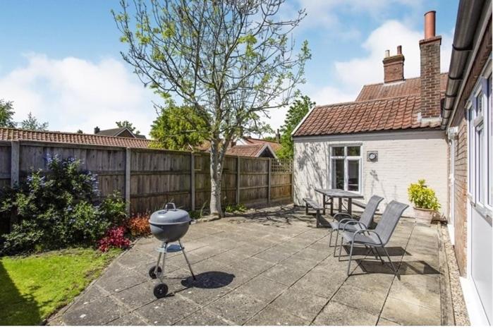 a backyard with a grill and chairs and a fence at Bakehouse in Great Ellingham