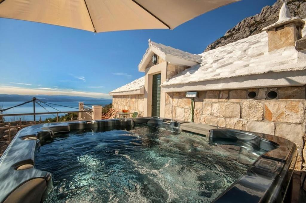 a hot tub in a backyard with an umbrella at Holiday Home Tonia in Baška Voda