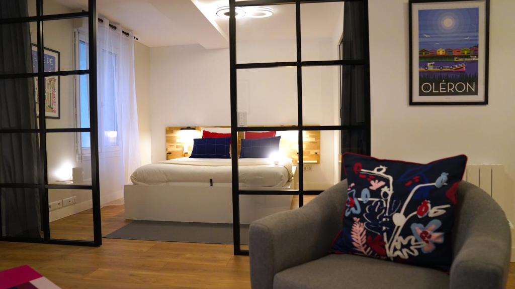 een slaapkamer met een bed en een stoel in een kamer bij Appartements Les Rochelais in La Rochelle