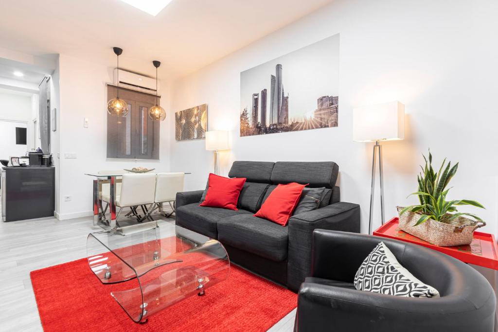 sala de estar con sofá negro y alfombra roja en Madrid Rio Apartment en Madrid