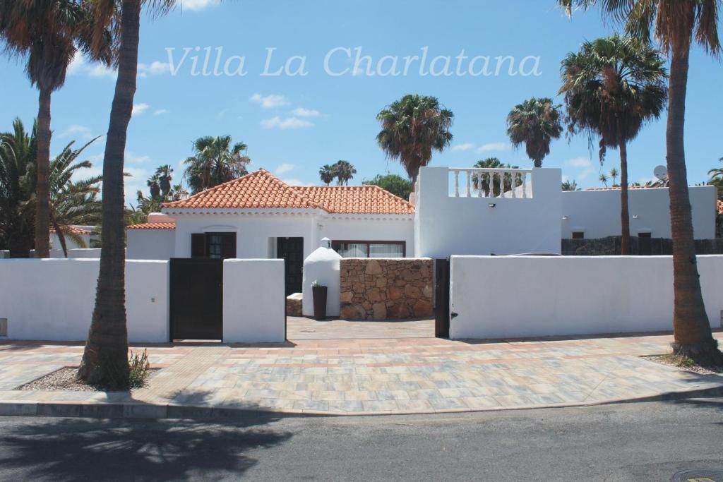 una casa blanca con palmeras delante en Villa La Charlatana en Caleta de Fuste