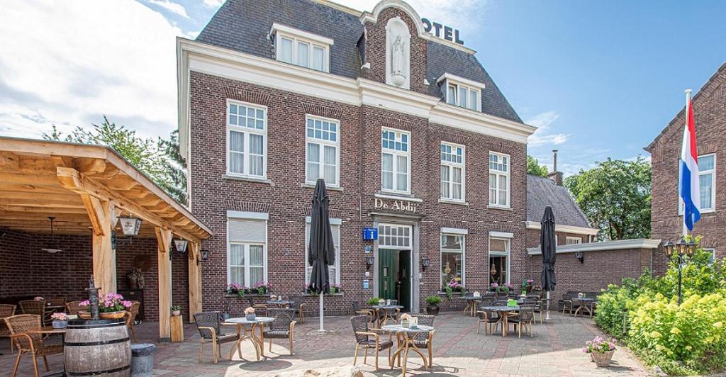 een bakstenen gebouw met tafels en stoelen ervoor bij Hotel de Abdij in Horn