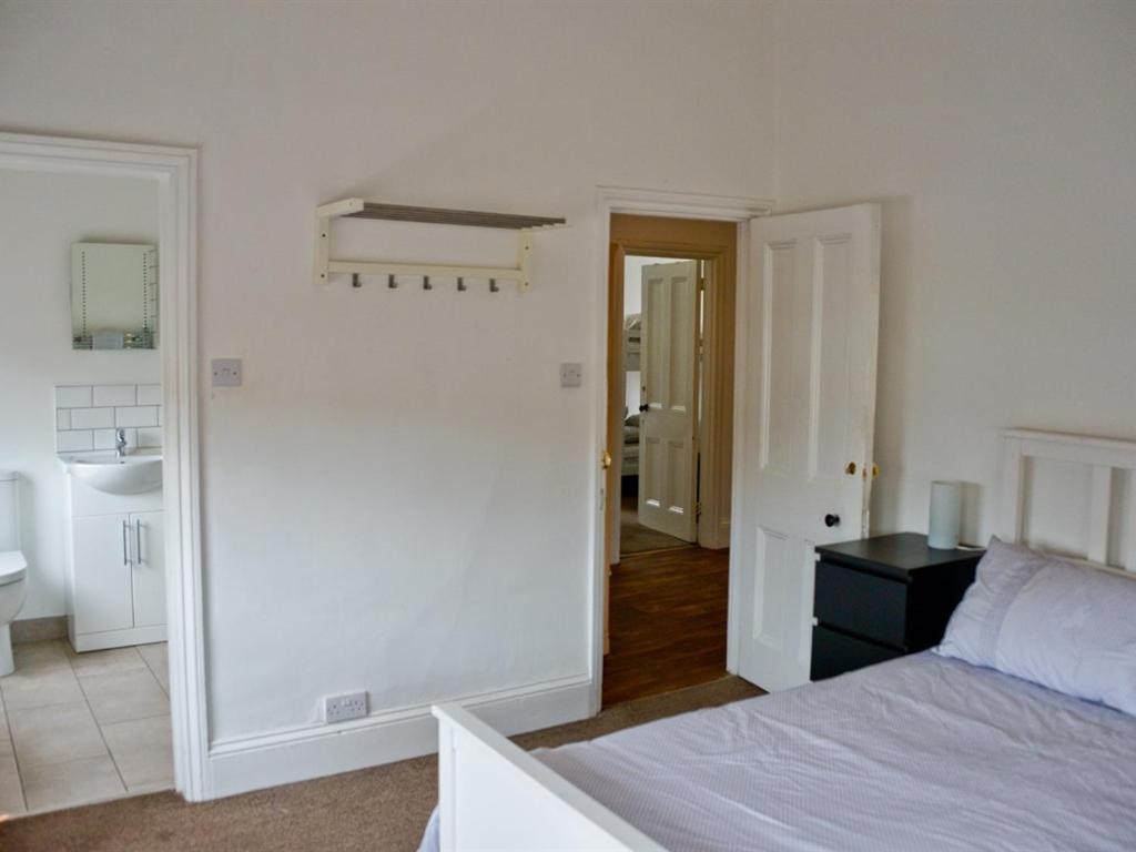a white bedroom with a bed and a sink at Corner House apartment in Worthing