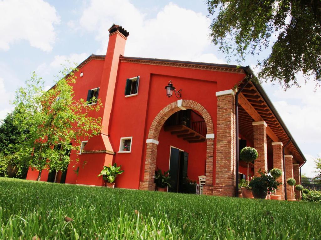 un edificio rojo con un arco delante de un patio en Borgo D'Asolo, en San Vito Di Altivole
