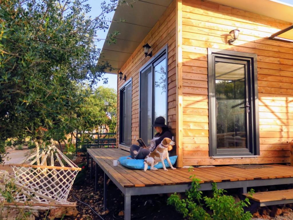 una mujer sentada en el porche de una casita con un perro en Karamel Tiny Houses, en Kas