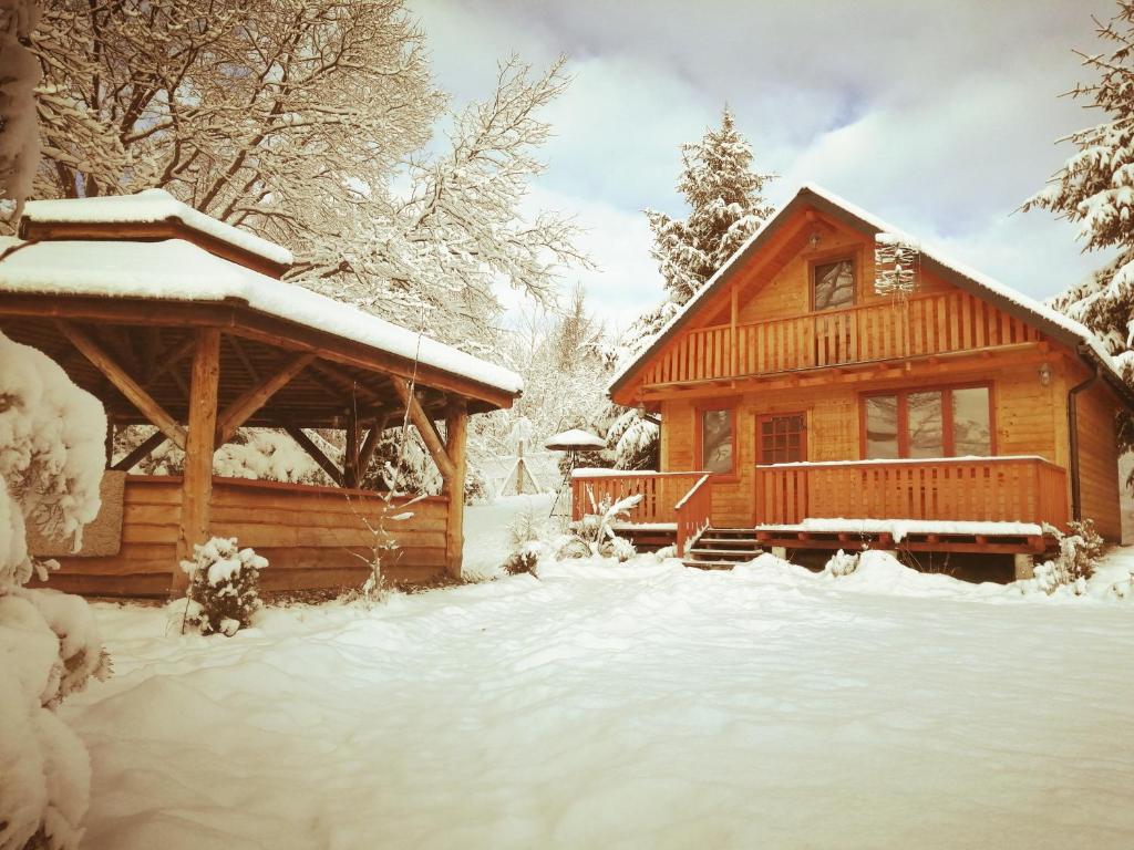 une cabane en rondins dans la neige avec une terrasse couverte dans l'établissement Chrząszczewo Widokowe wzgórze 2, à Uherce Mineralne