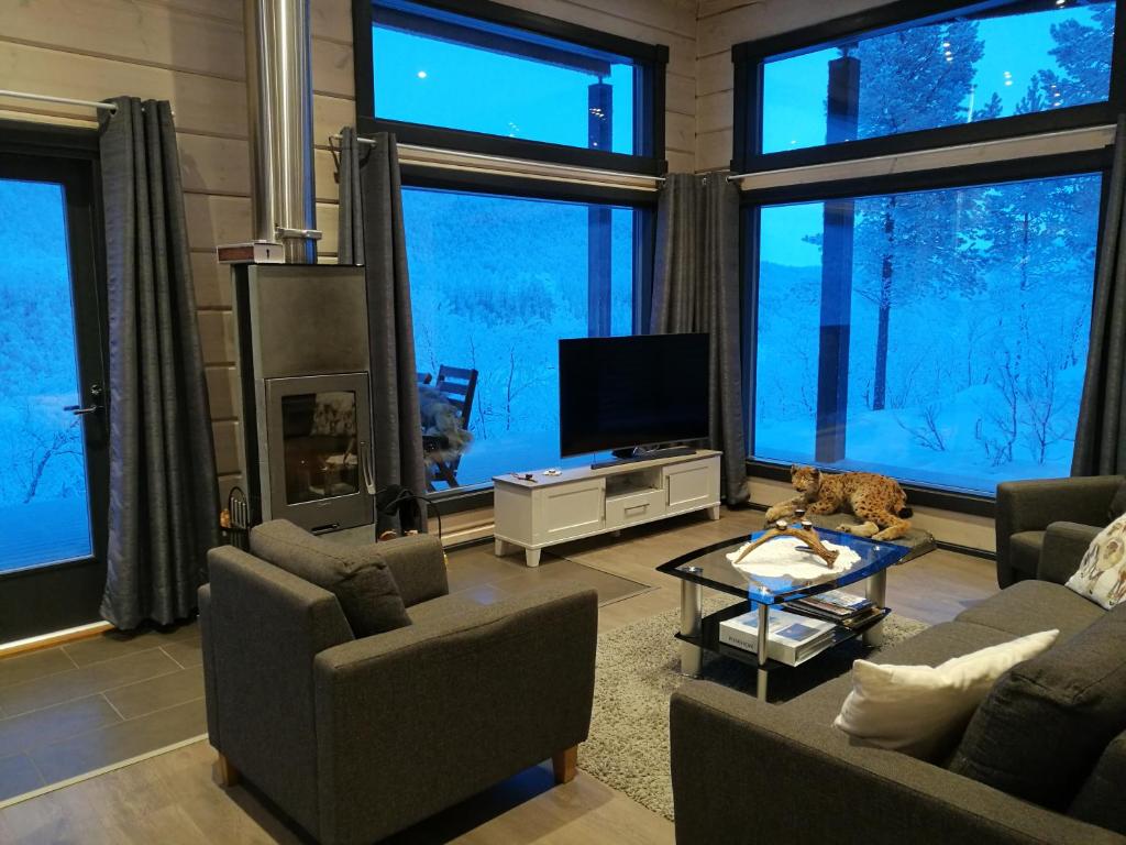 a living room with couches and a tv and large windows at Lomatärppi in Utsjoki