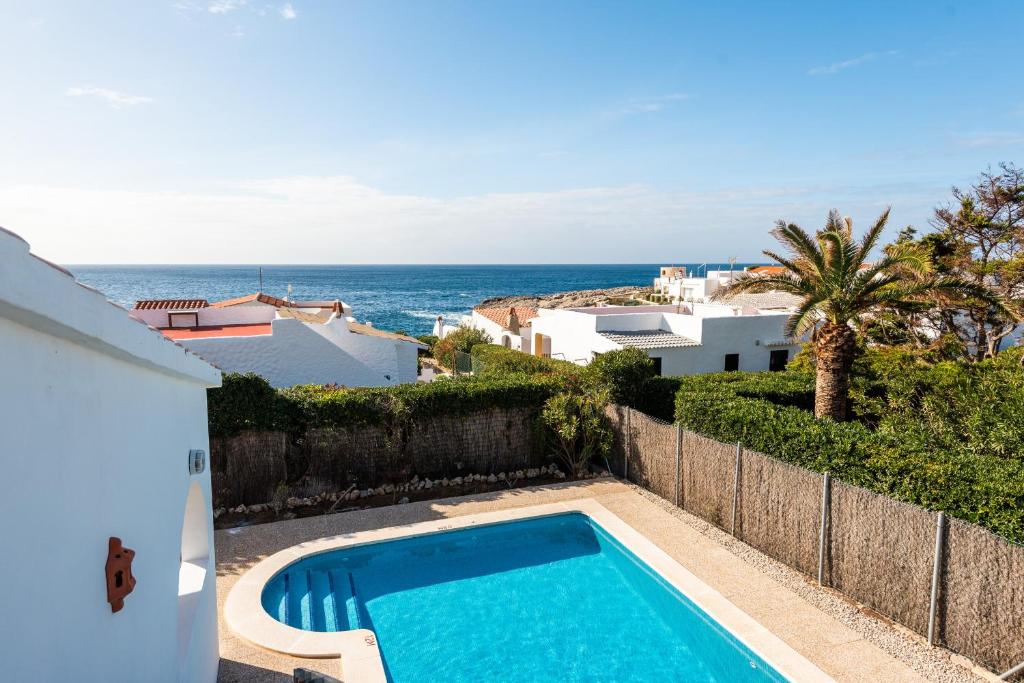 a swimming pool with the ocean in the background at Casa Blanca in Sant Lluis