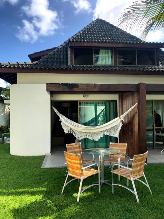 une terrasse avec des chaises et une table en face d'une maison dans l'établissement Bangalô Luxo Beach Class Resort Muro Alto, à Porto de Galinhas