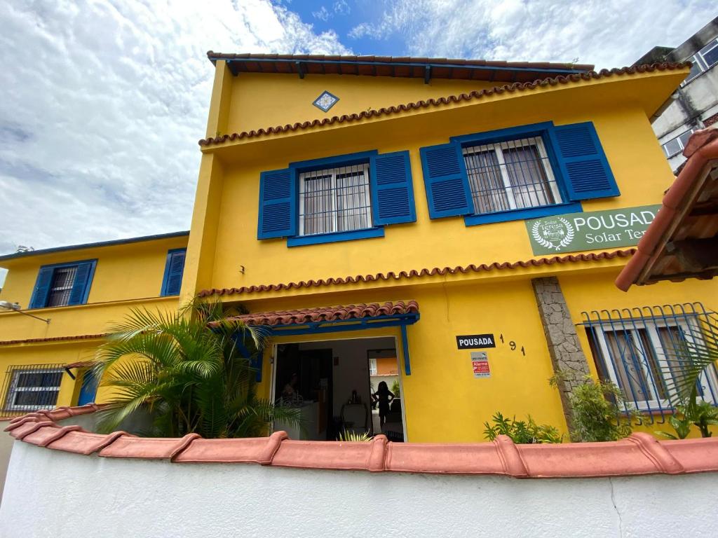 ein gelbes Gebäude mit blauen Fensterläden darauf in der Unterkunft Pousada Solar Teresa in Petrópolis