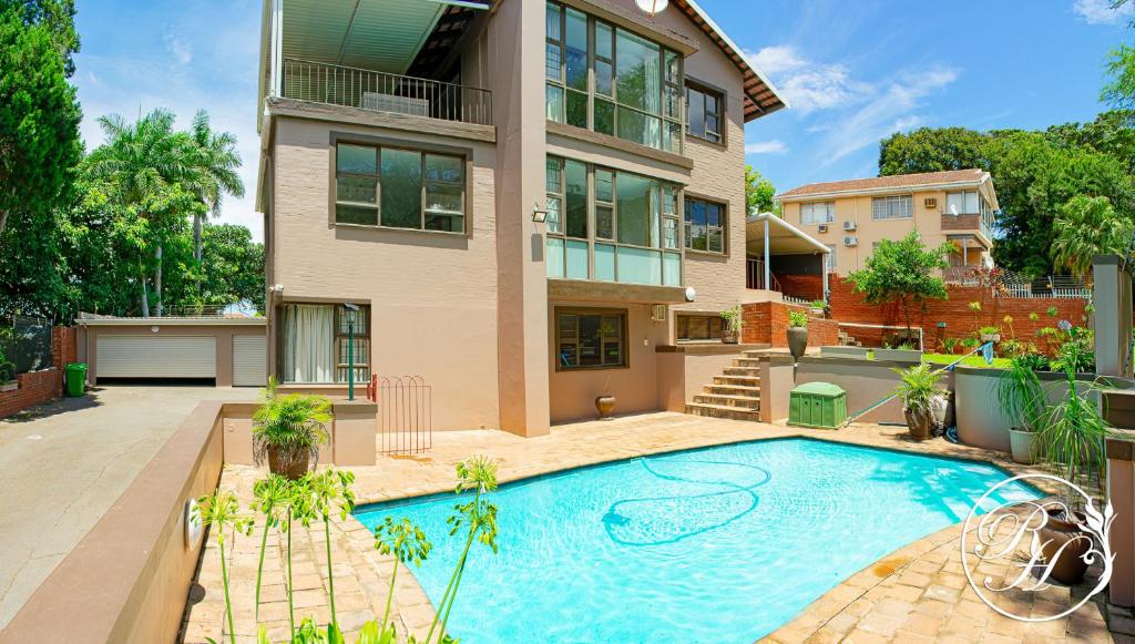 a house with a swimming pool in front of it at Roseland House Self Catering in Durban
