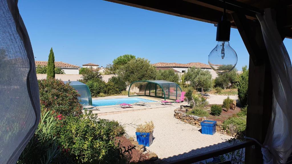 a view of a swimming pool through a window at CHAMBRE D’HÔTES NATURE ET SAVEURS in Boutenac