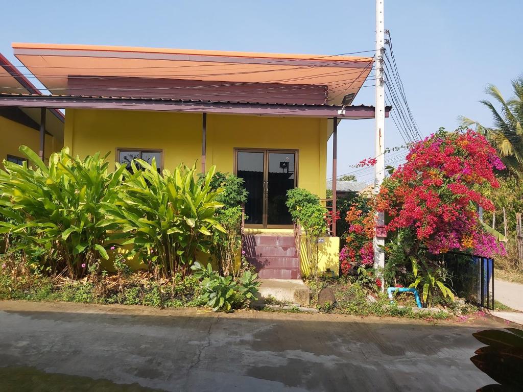 una pequeña casa amarilla con plantas y flores en Lucky Home Prakhon Chai en Prakhon Chai