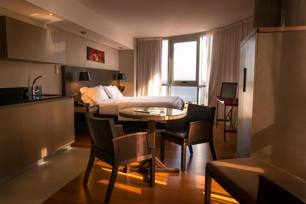 モンテビデオにあるAXSUR Design Hotelのベッド、テーブル、椅子が備わる客室です。