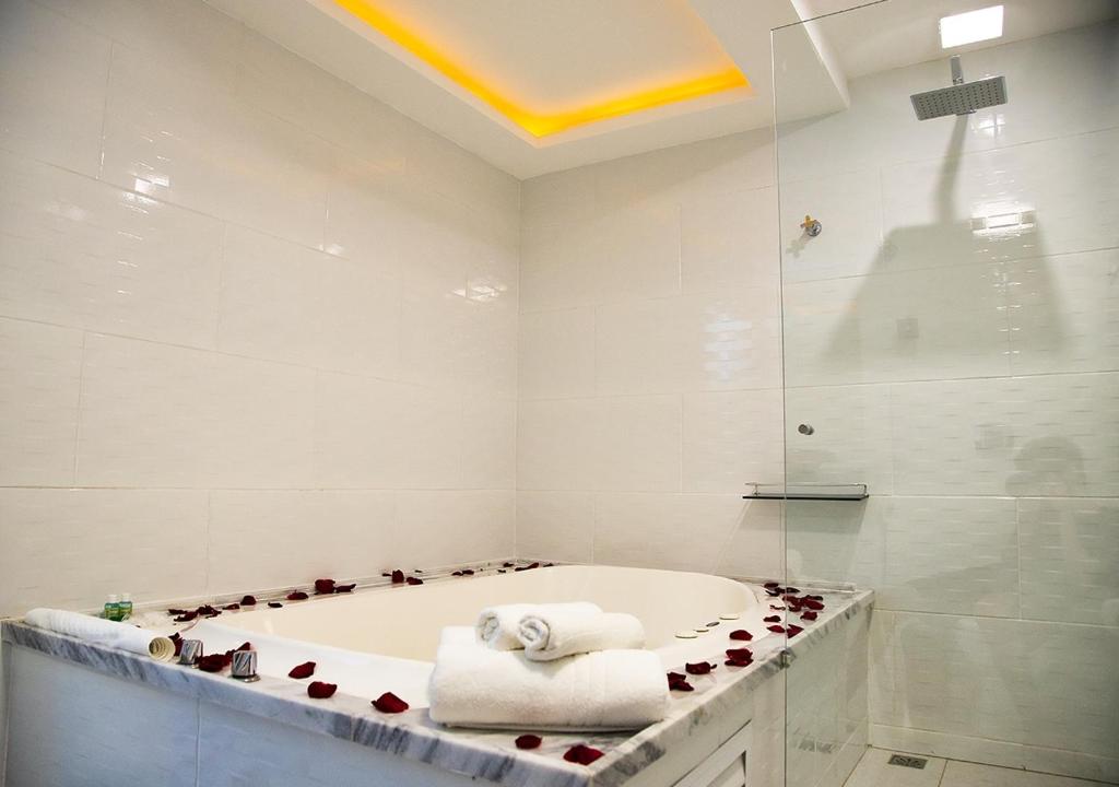 y baño blanco con bañera y ducha. en Pousada de Itaipava en Itaipava