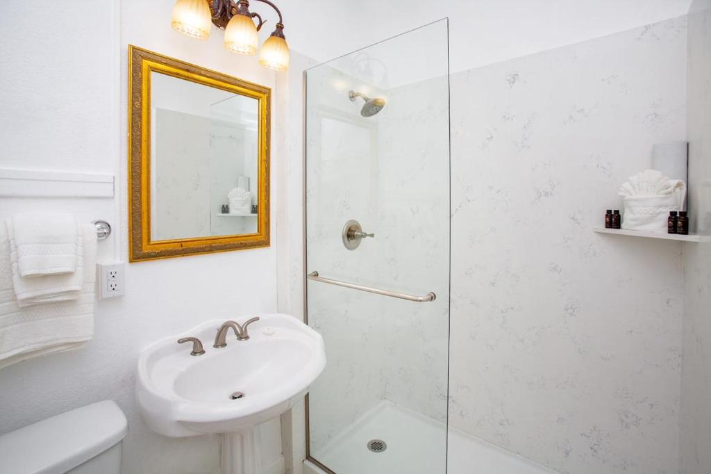 a white bathroom with a sink and a shower at MarQueen Hotel in Seattle