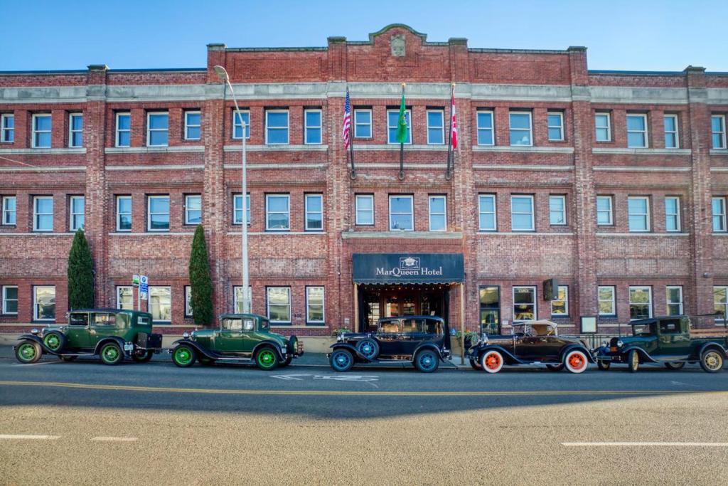 a group of old cars parked in front of a building at MarQueen Hotel in Seattle