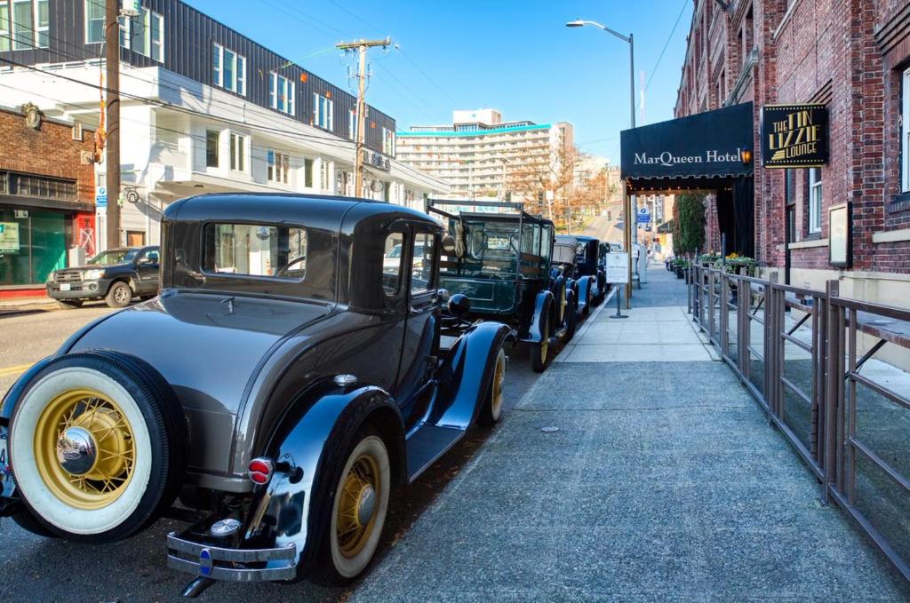 two old cars parked on the side of a street at MarQueen Hotel in Seattle