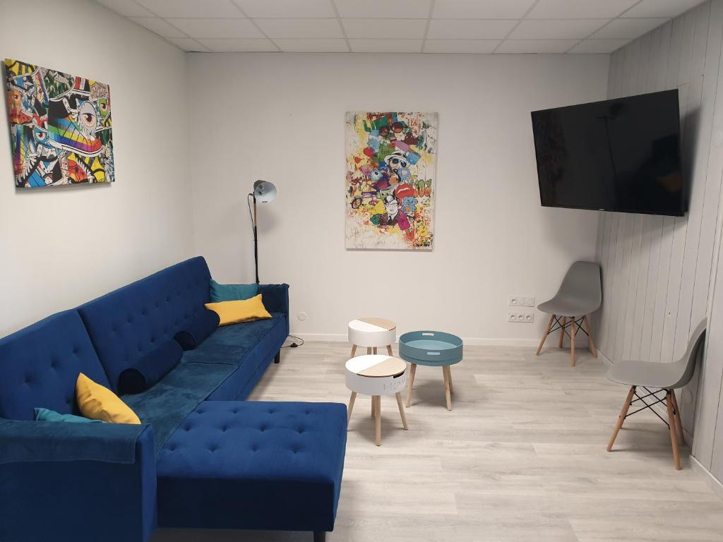 ein Wohnzimmer mit einem blauen Sofa und einem Flachbild-TV in der Unterkunft Modernité et élégance - Appartement - WIFI in Issoire