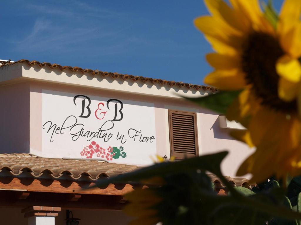 a sign on the side of a building with a sunflower at B&B Nel Giardino In Fiore in Castiadas