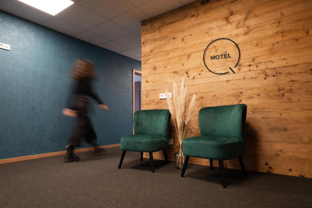 a woman walking past two chairs in a waiting room at Motel Q in Rottweil