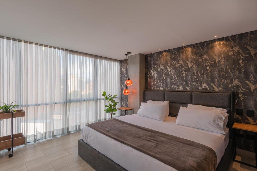 a bedroom with a large bed and a large window at VPV Suites in Medellín