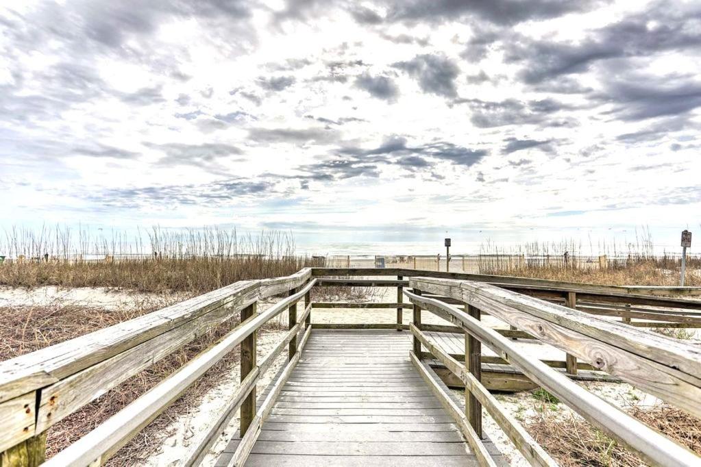 - un pont en bois sur la plage avec un ciel nuageux dans l'établissement Ocean Front, Private Balconies, à Myrtle Beach