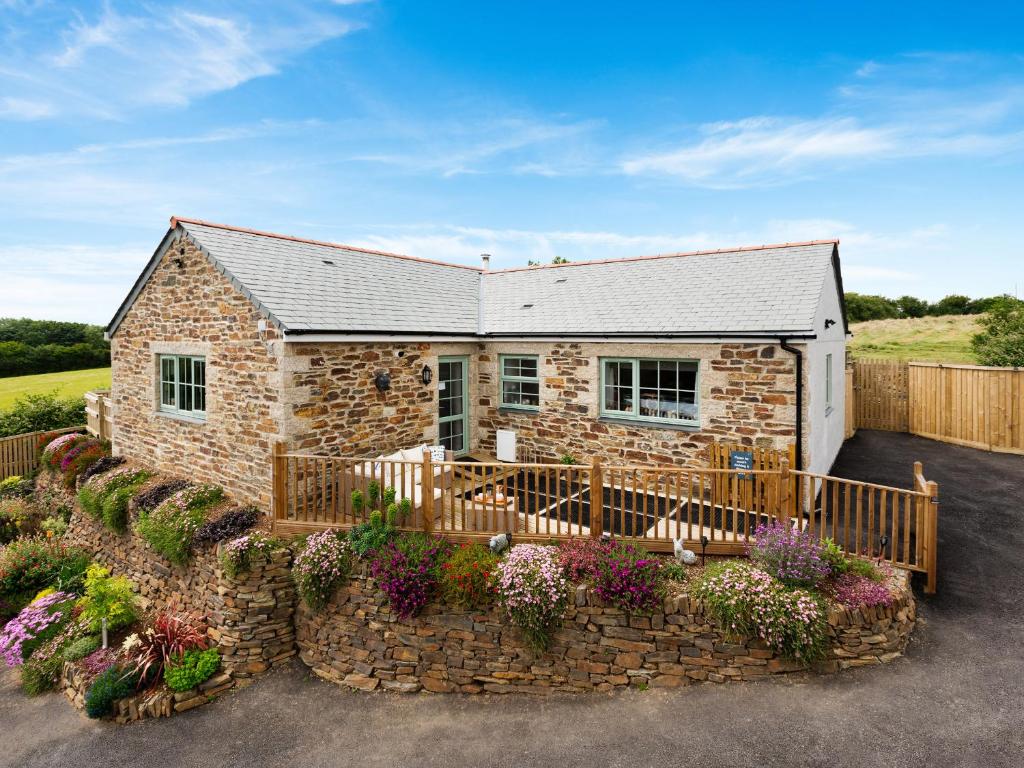 a stone house with a stone fence and flowers at Bear Cottage in Truro