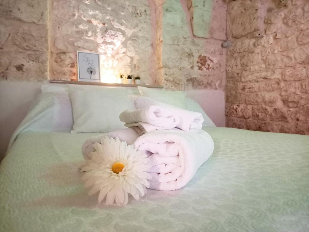 un letto con asciugamani e un fiore sopra di La Vernèa a Ceglie Messapica