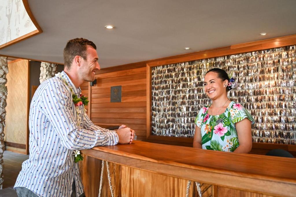 
a man standing next to a woman in front of a counter at Le Bora Bora by Pearl Resorts in Bora Bora
