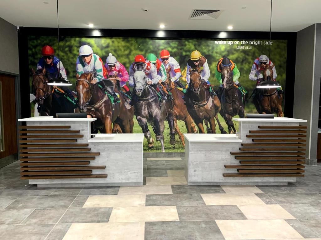 a large painting of a horse race on a wall at La Quinta Inn & Suites by Wyndham Louisville NE - Old Henry Rd in Louisville