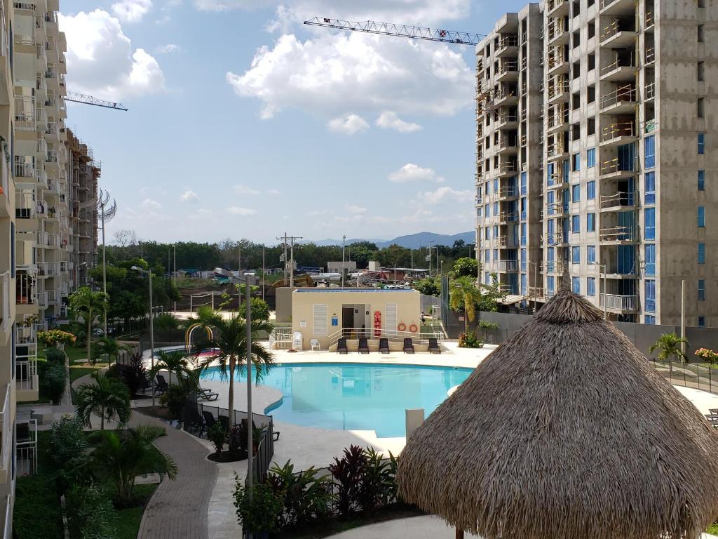 a swimming pool with a straw umbrella and some buildings at Piscina & Descanso - Puerto Azul- con todas las comodidades! in Ricaurte