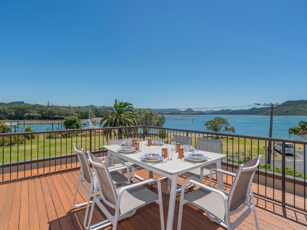 a table and chairs on a deck with a view of the water at Harbourside Haven - Whangamata Holiday Home in Whangamata