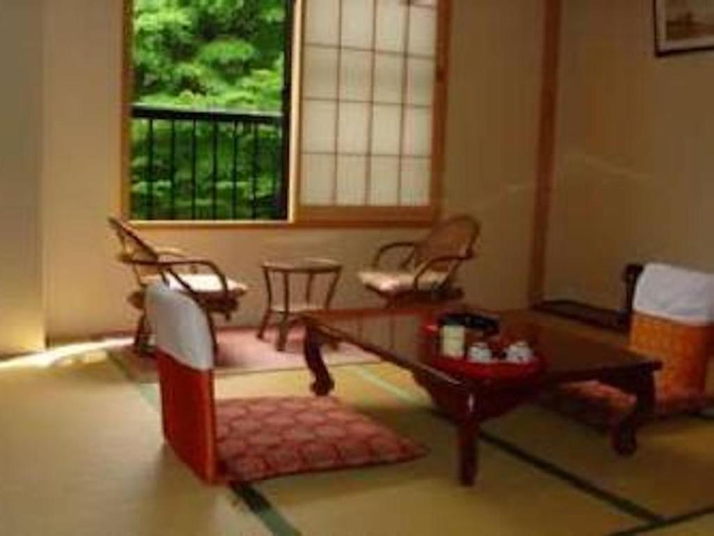 ein Wohnzimmer mit einem Tisch, Stühlen und einem Fenster in der Unterkunft Ichigekan / Vacation STAY 8470 in Nakanojo