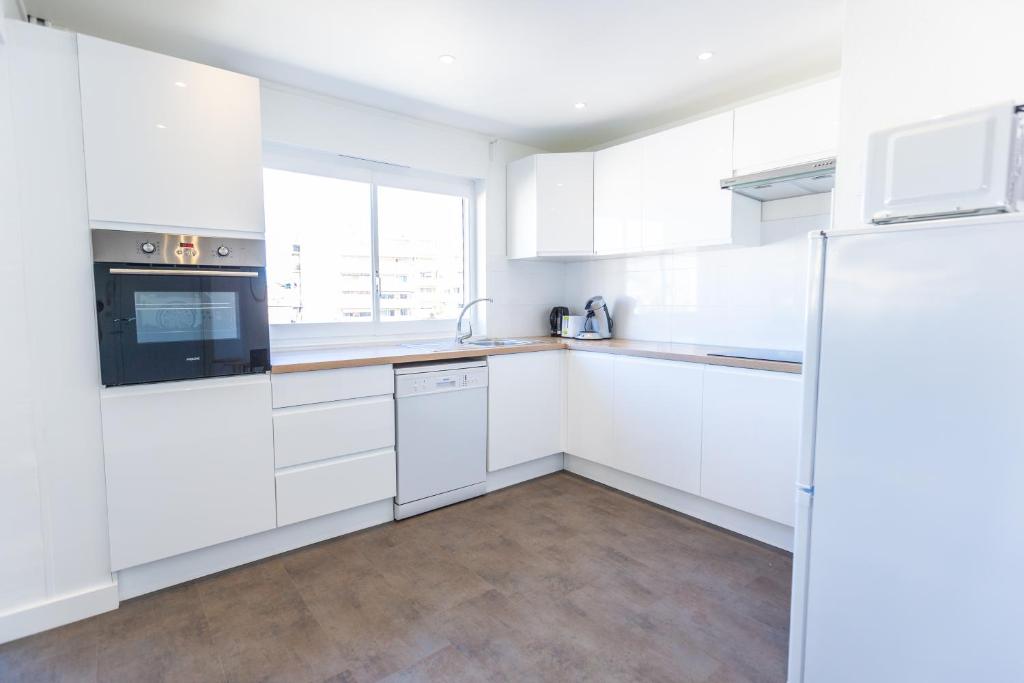 a white kitchen with white cabinets and a refrigerator at Superbe 100m2 - 2 Balcons - Proche Gare - Climatisé in Marseille