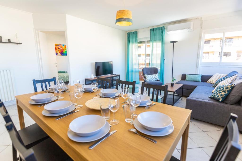 a dining room with a table with plates and wine glasses at Superbe 100m2 - 2 Balcons - Proche Gare - Climatisé in Marseille