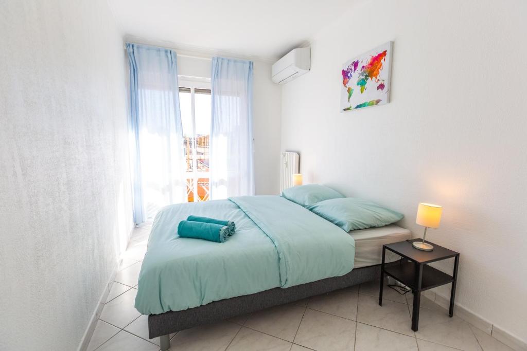 a bedroom with a bed with blue sheets and a window at Superbe 100m2 - 2 Balcons - Proche Gare - Climatisé in Marseille