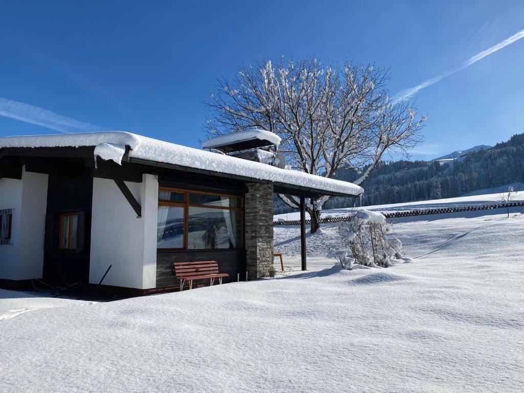 a snow covered cabin with a bench in the snow at Wohlfühlchalet Tirol in Reith im Alpbachtal