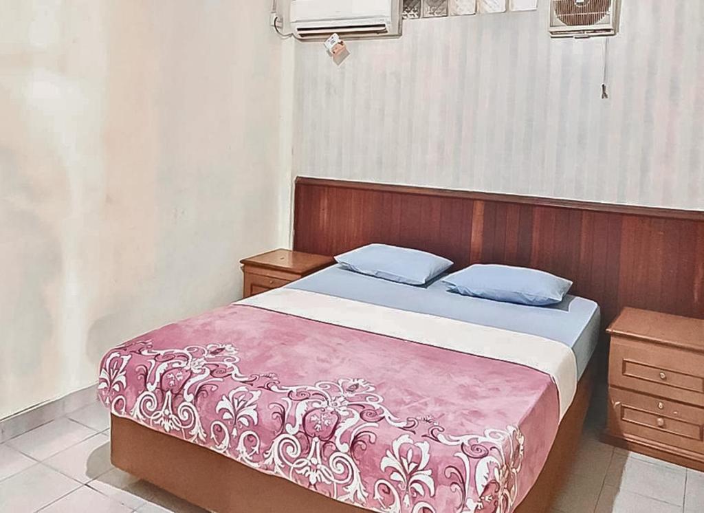 a bedroom with a bed with a wooden head board at Hotel Aida Syariah Mitra RedDoorz in Samarinda