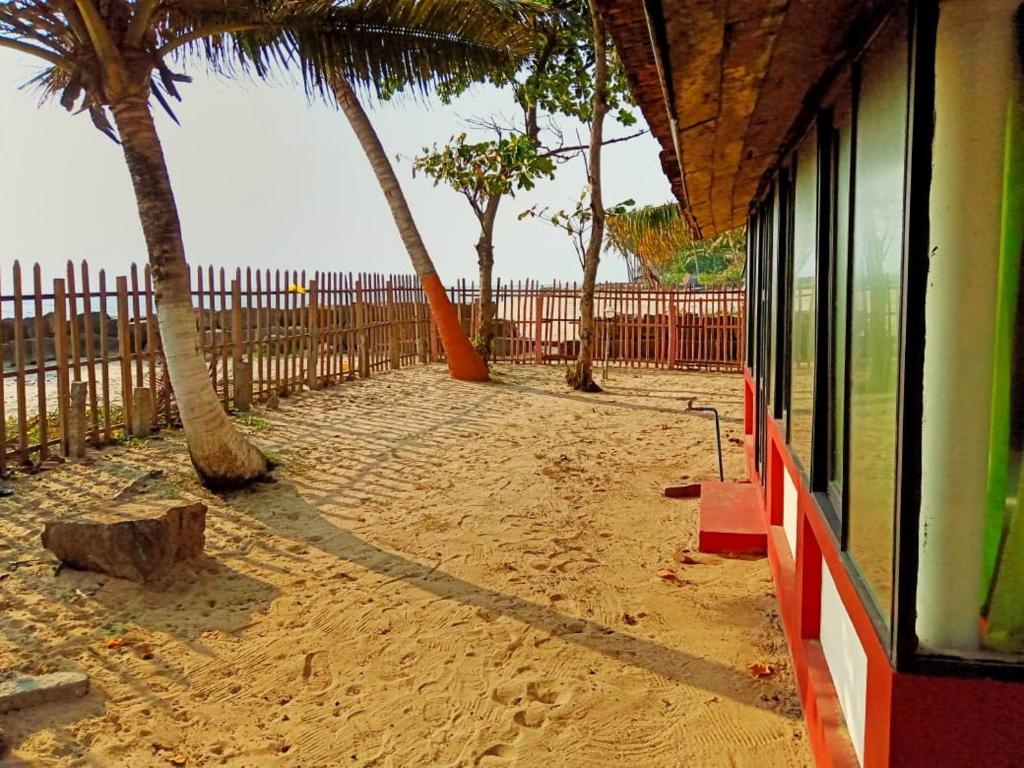 einen Strand mit Palmen und einem Zaun in der Unterkunft SAMBODHI YOGA RETREAT in Alappuzha