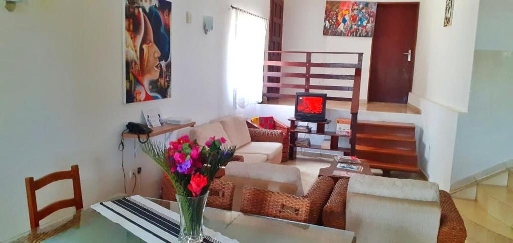 uma sala de estar com um vaso de flores sobre uma mesa em casa Luis em São Tomé