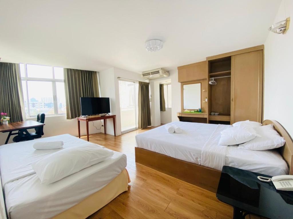 a hotel room with two beds and a television at City Residence in Bangkok