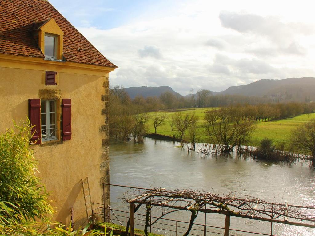 a view of a river with a building and a house at Maison O'Galop in Beynac-et-Cazenac
