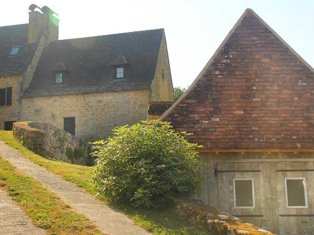 stary kamienny budynek z brązowym dachem w obiekcie Maison Linol w mieście Beynac-et-Cazenac