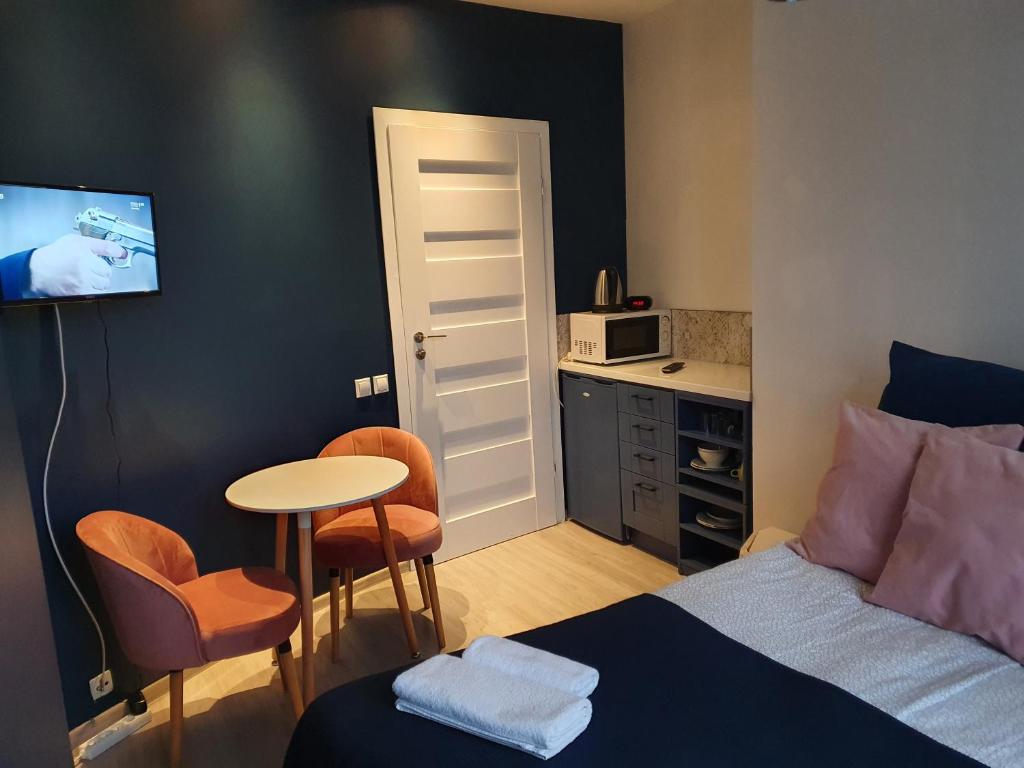 a bedroom with a bed and a table and a kitchen at EURO-ROOM in Krakow